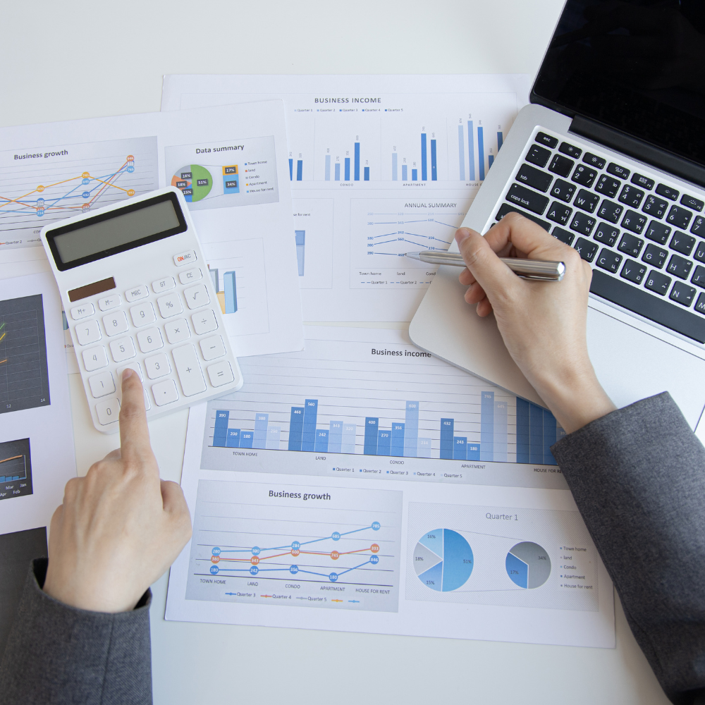 Overhead view of business person working on computer and graphs